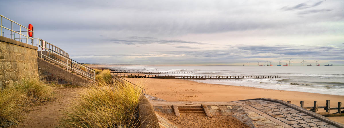 Steps leading down to Aberdeen Beach from the esplanade, with marram grass, wooden groynes and offshore wind turbines