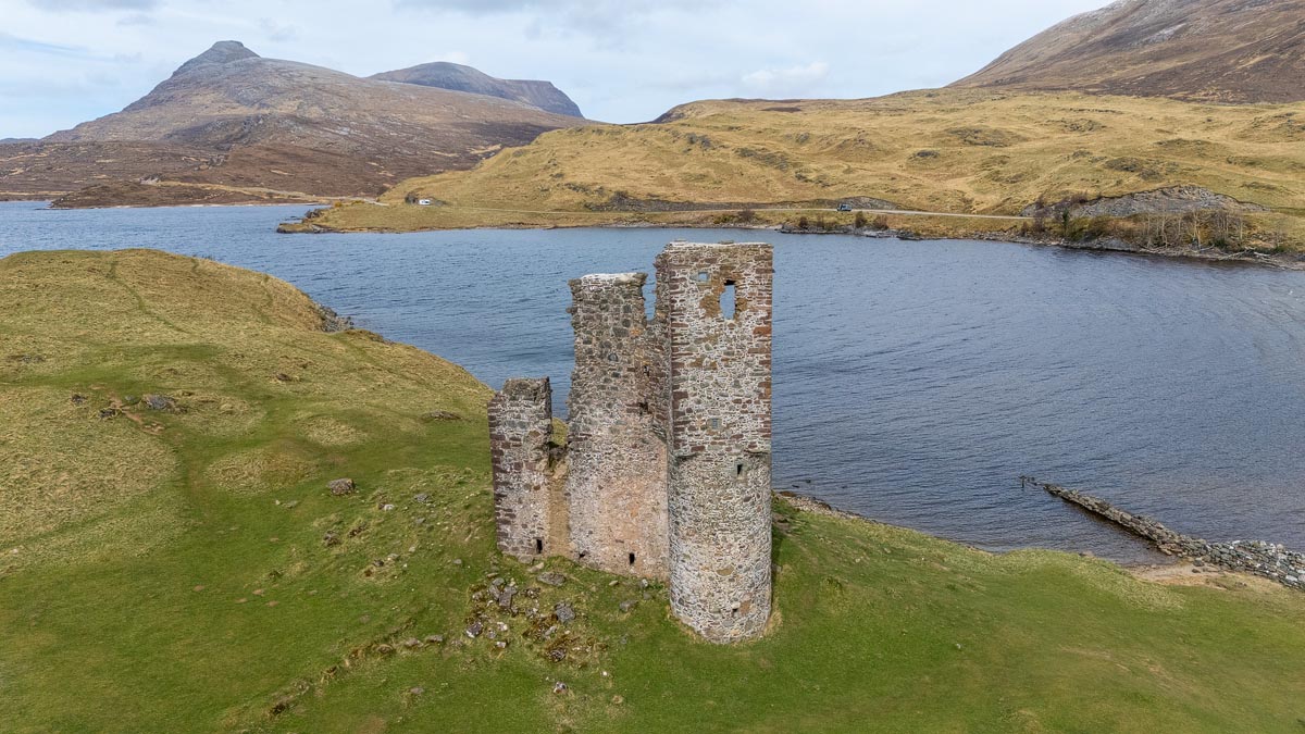 Aerial drone view of Ardvreck Castle tower with Loch Assynt and the mountains of Quinag in the background