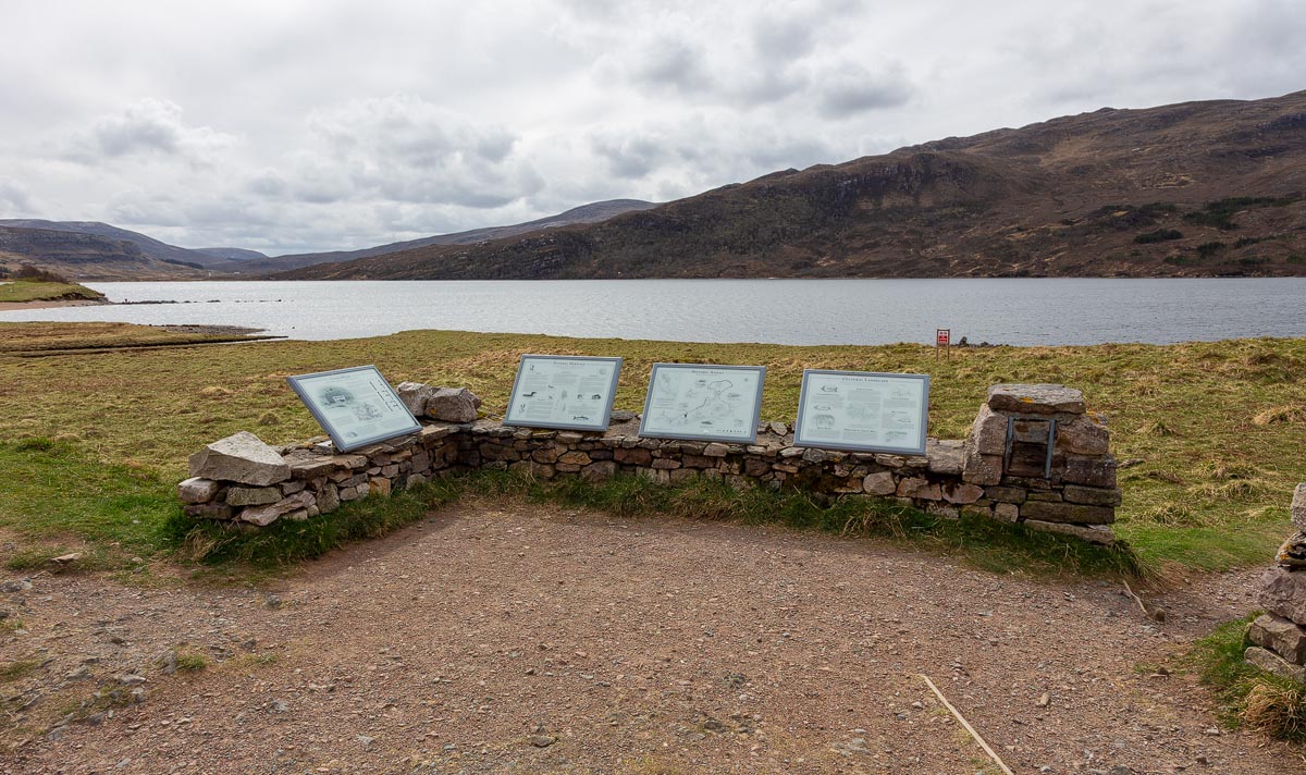 Information boards mounted on a stone wall at Ardvreck Castle overlooking Loch Assynt