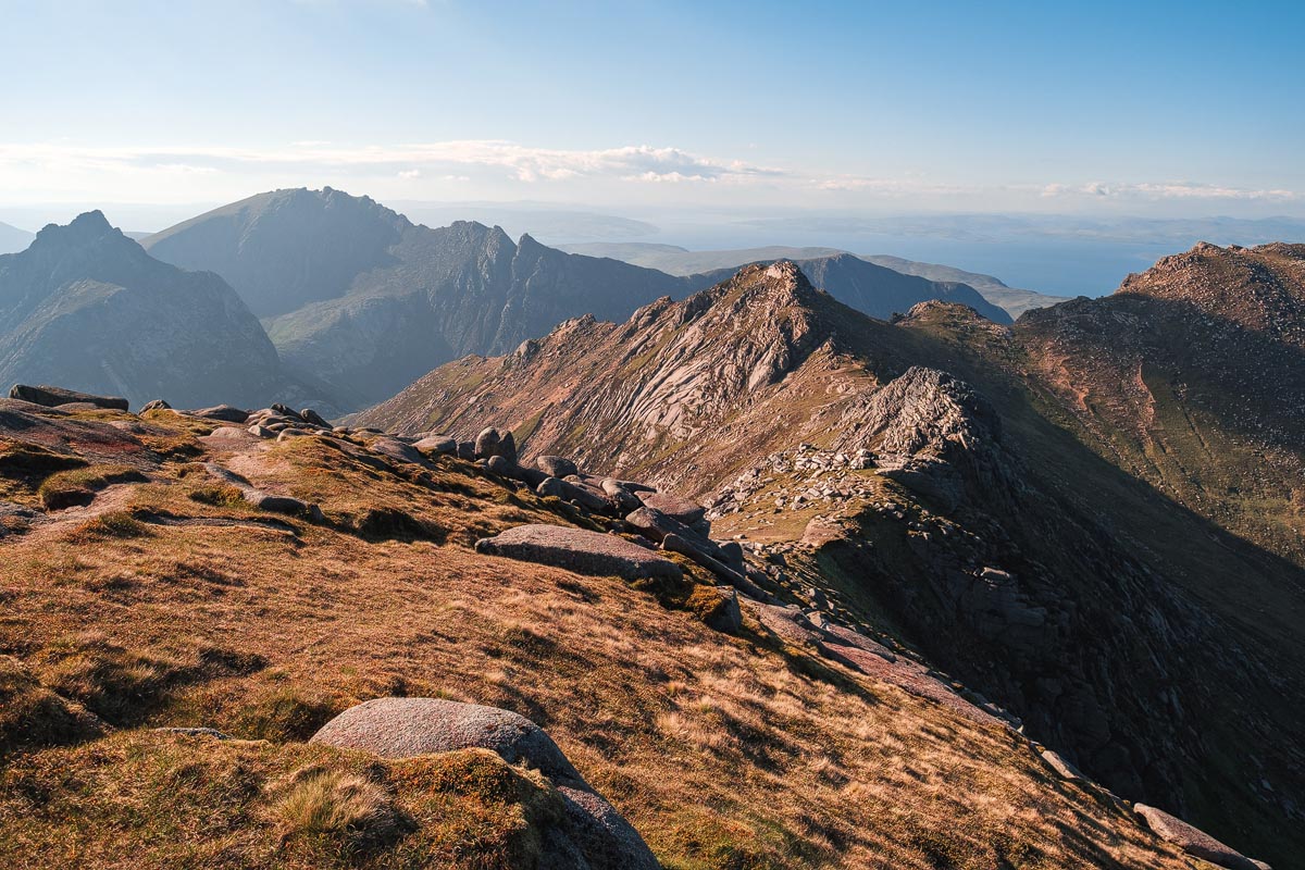 View from the summit of Goatfell on the Isle of Arran looking along the jagged granite ridge with dramatic mountain peaks and sea views beyond