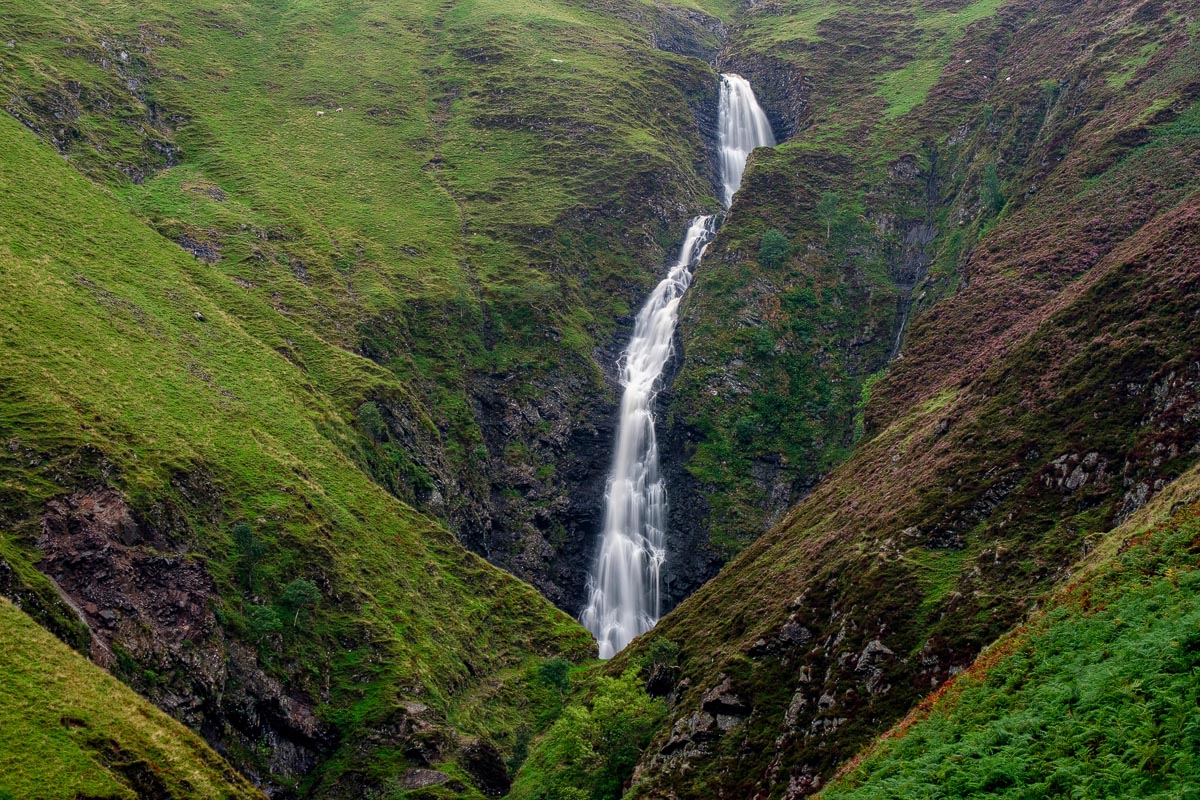 Grey Mare's Tail waterfall plunging dramatically down a steep green hillside in the Moffat Hills in southern Scotland