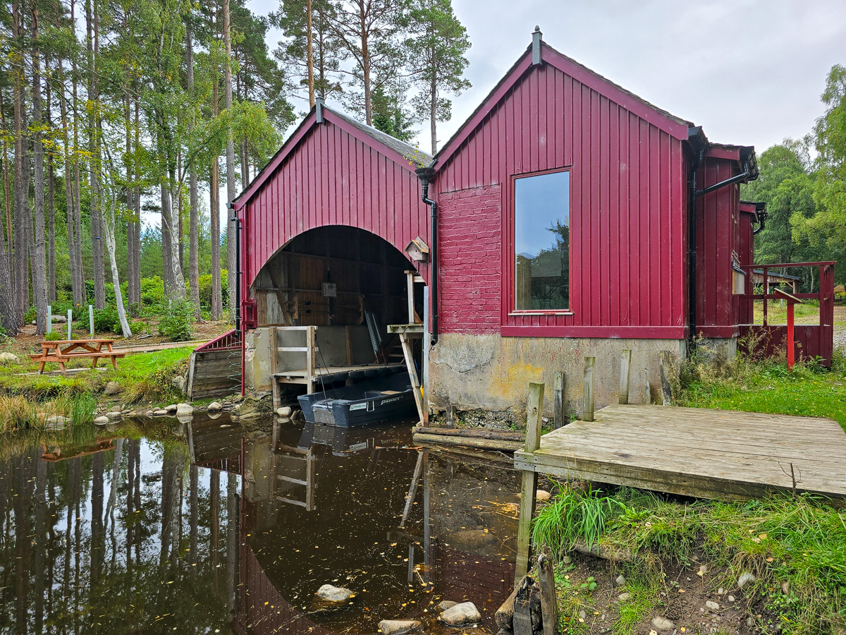 Red Victorian boathouse with an arched boat bay and a fishing boat moored inside