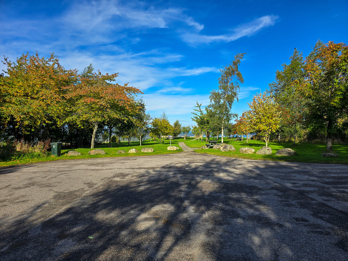 Gravel car park at Califer Hill Viewpoint with boulders, trees and a green wheelie bin