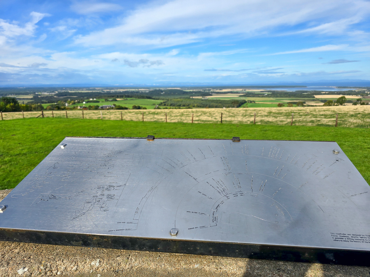 Steel viewfinder plate on its plinth with farmland and the Moray Firth beyond