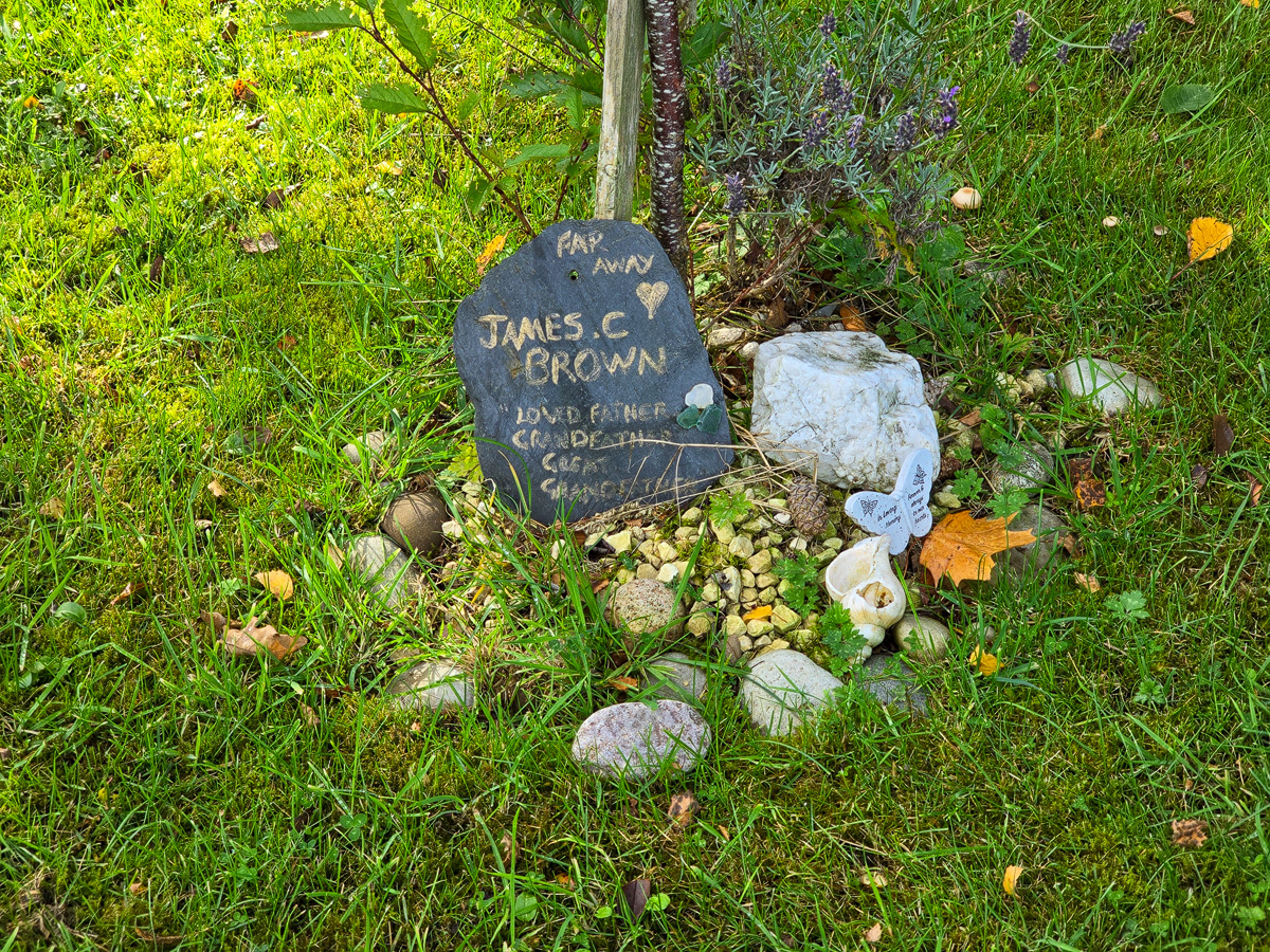 Handwritten memorial slate among stones and lavender at Califer Hill