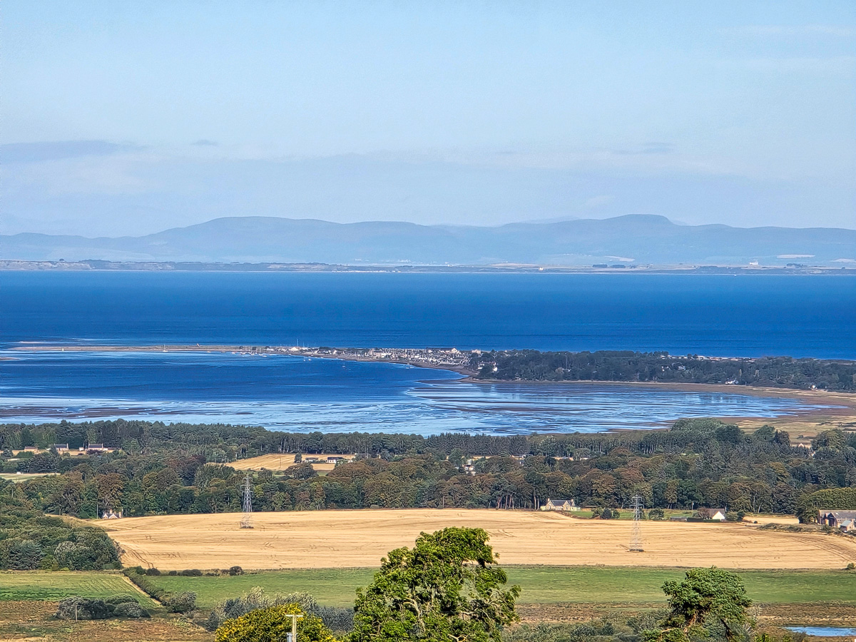Zoomed view of Findhorn village on its spit between Findhorn Bay and the Moray Firth with hills beyond