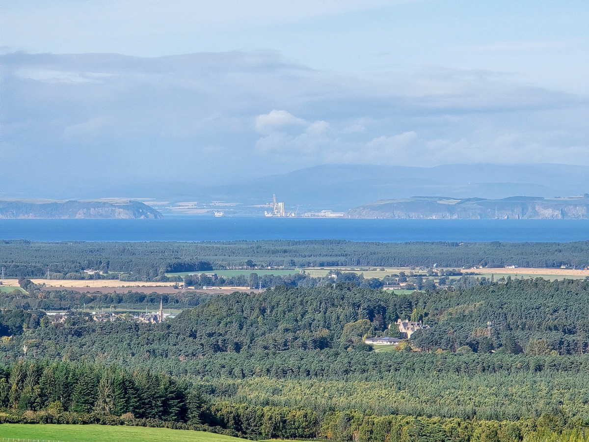 Brodie Castle among trees with Culbin Forest and the Sutors of Cromarty beyond
