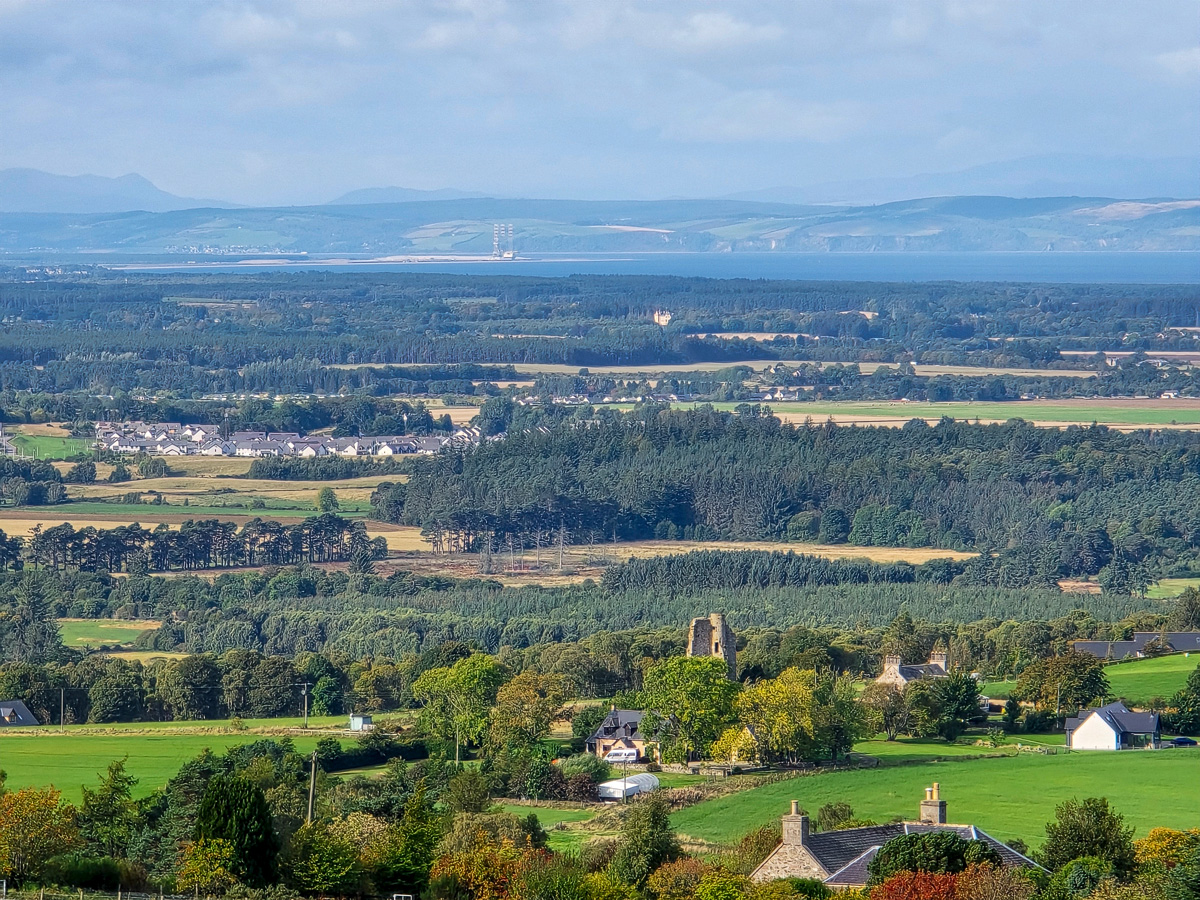 Ruined tower of Blervie Castle among fields with Forres and the Cromarty Firth beyond