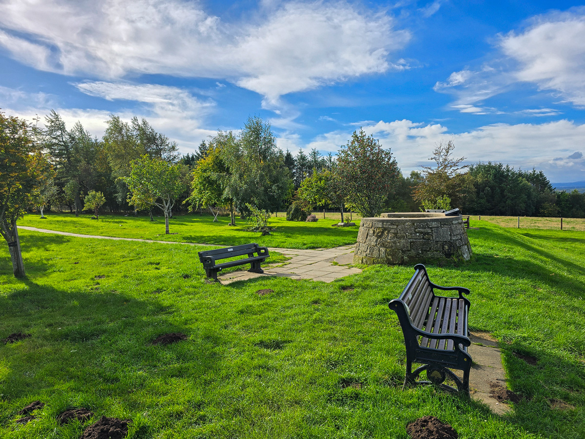 Circular stone viewfinder plinth surrounded by benches and trees at Califer Hill