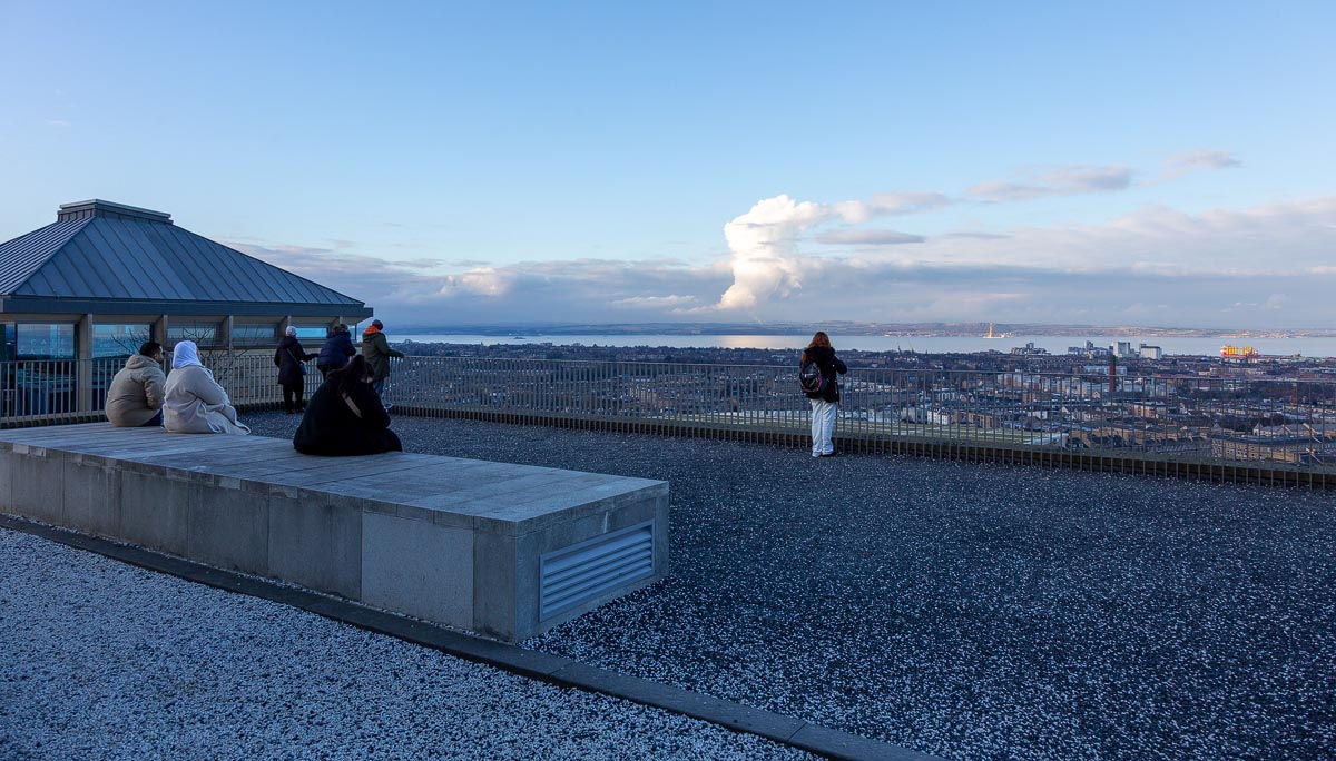 Visitors enjoying the viewing terrace at the Collective on Calton Hill, looking north across Edinburgh to the Firth of Forth