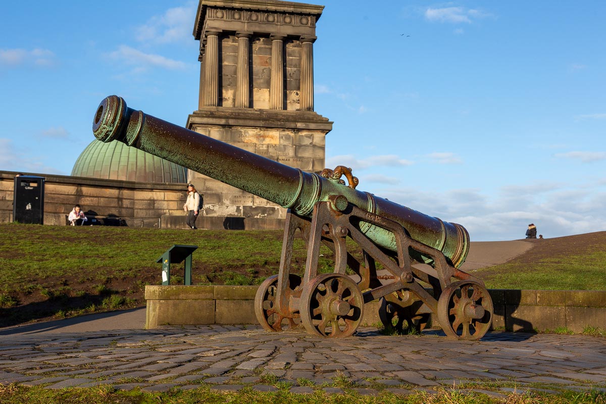 A historic cannon on Calton Hill with the base of the National Monument behind