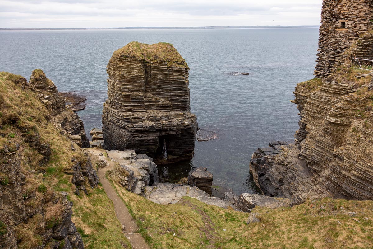 Dramatic sea stack and geo beside Castle Sinclair Girnigoe showing layered Old Red Sandstone geological formations