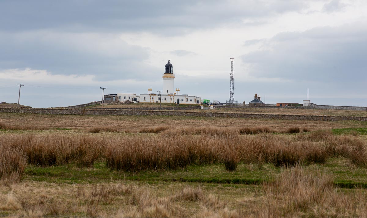 Noss Head Lighthouse seen across moorland from the walking path to the castle