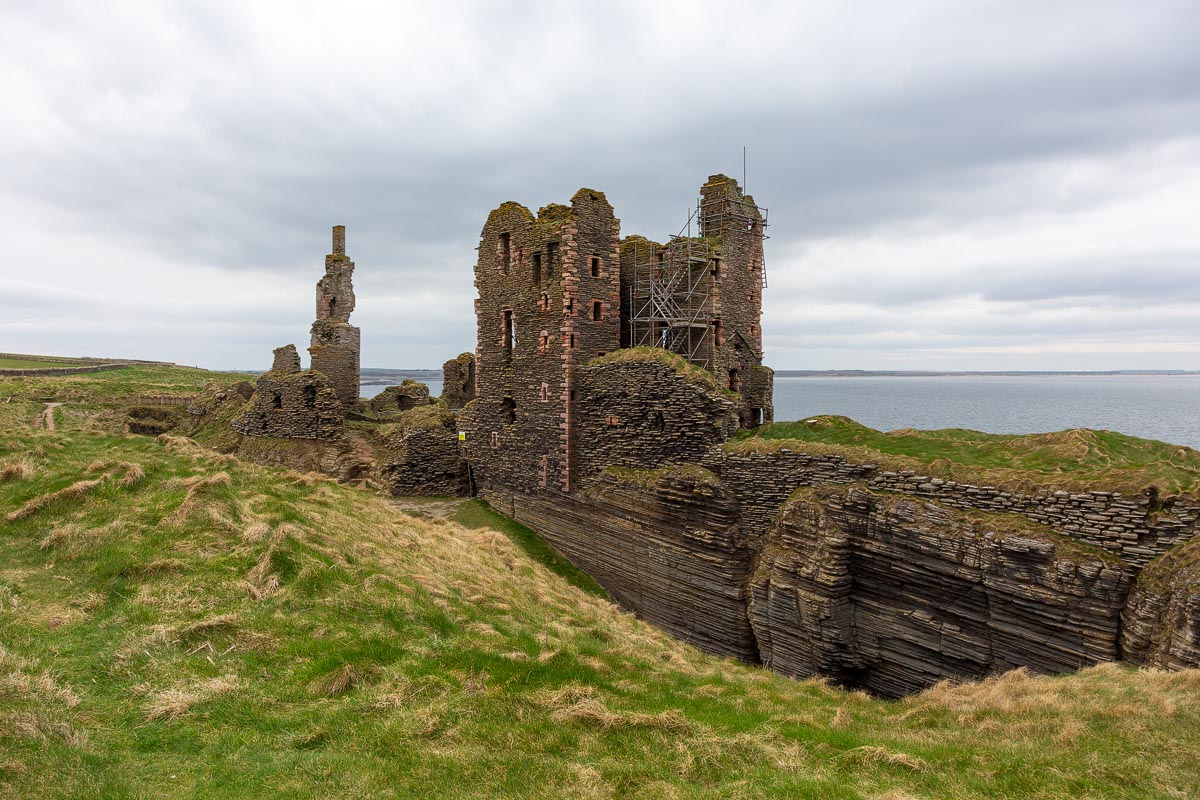 Close-up view of Castle Sinclair Girnigoe tower house and ruins showing layered sandstone cliffs and rock-cut ditch