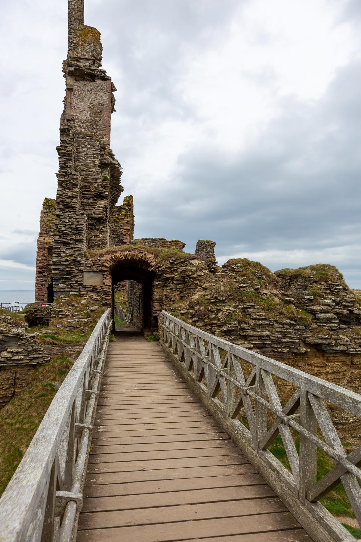 The wooden footbridge leading across the rock-cut ditch to the arched entrance of Castle Sinclair Girnigoe
