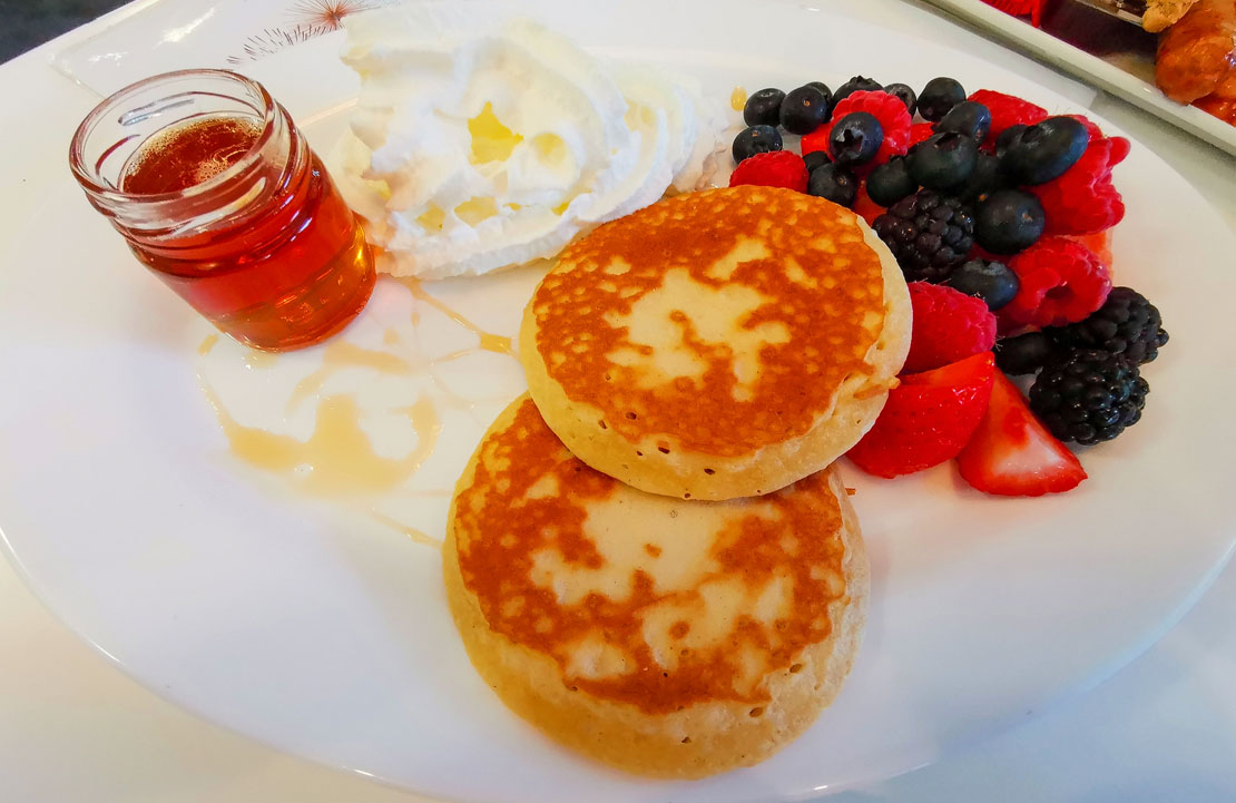 Pancakes with fruit and maple syrup.