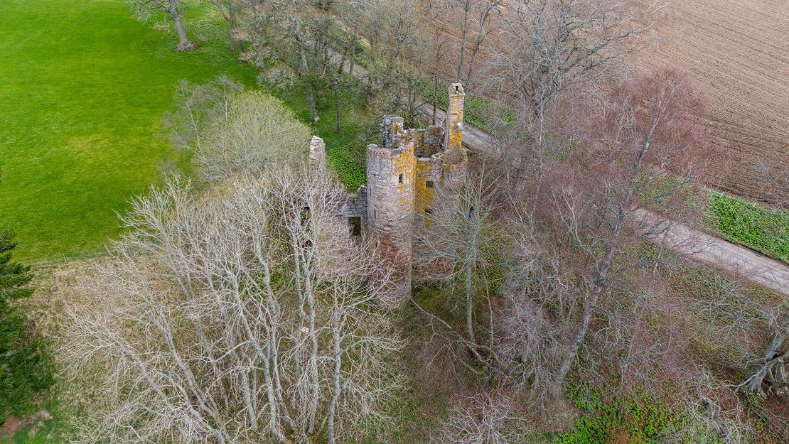 Drone photo showing Corse Castle nestled in its woodland setting with Aberdeenshire farmland beyond