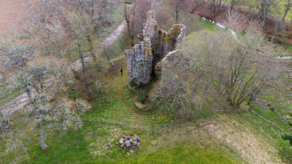Aerial view of Corse Castle with a visitor for scale – the Corse Burn is visible to the right