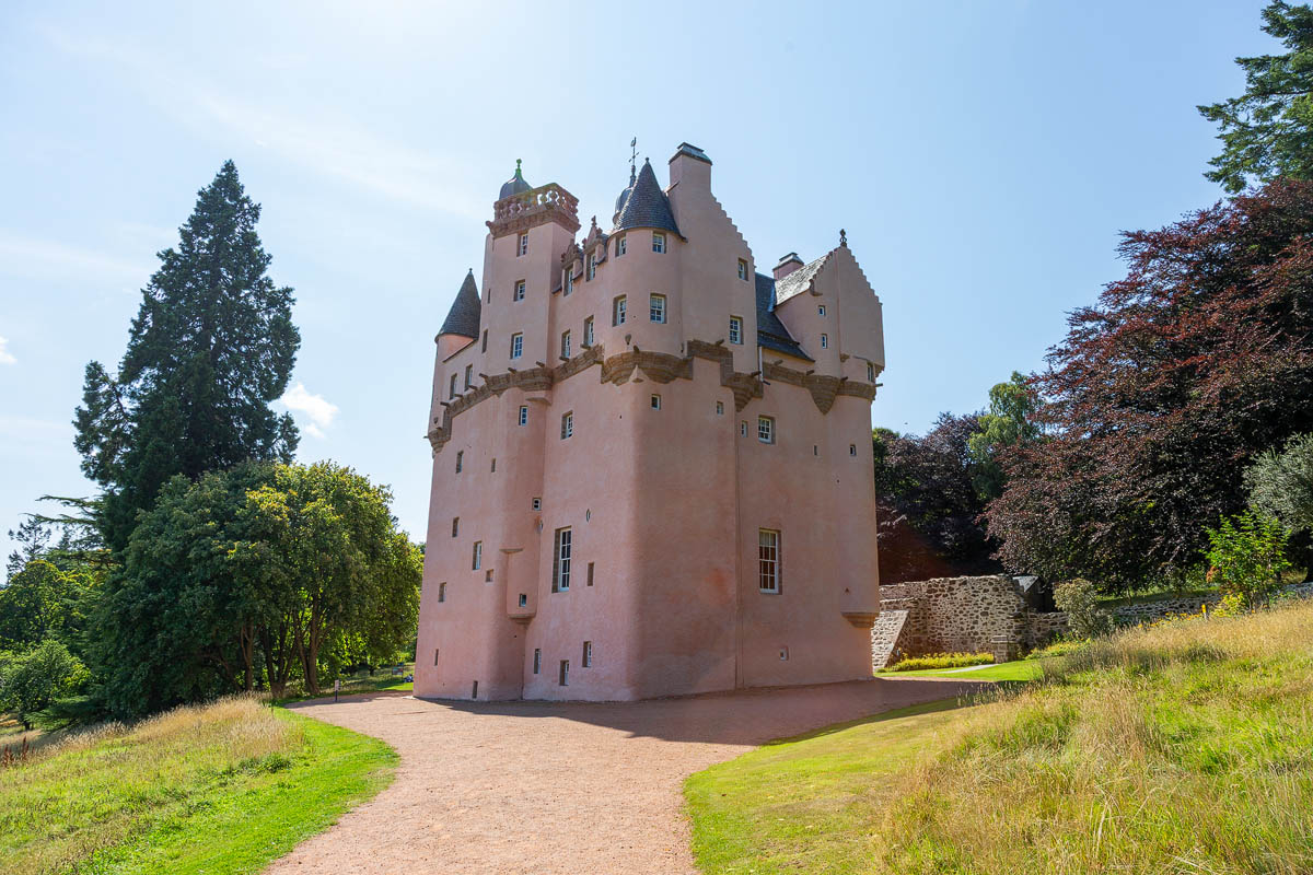 Craigievar Castle front view showing the iconic pink-harled tower house with turrets and conical roofs set against a blue sky