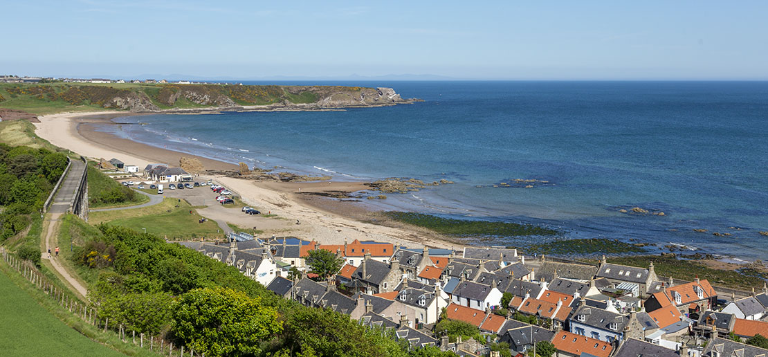 Elevated view over Cullen sea town with its traditional stone houses and orange roofs, the beach curving around the bay
