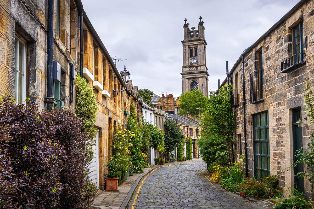 The charming cobbled Circus Lane in Stockbridge with St Stephen's Church tower visible in the background