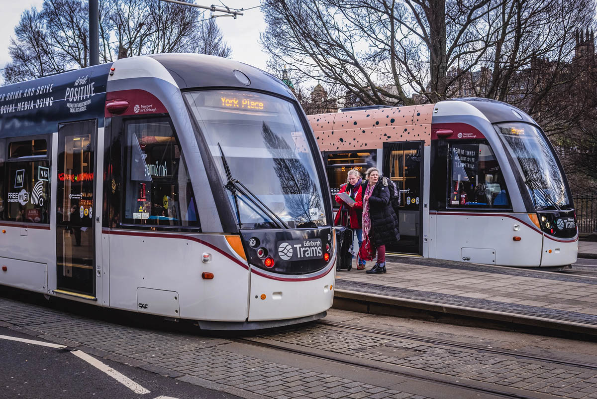 Two Edinburgh Trams at a city centre stop with passengers boarding