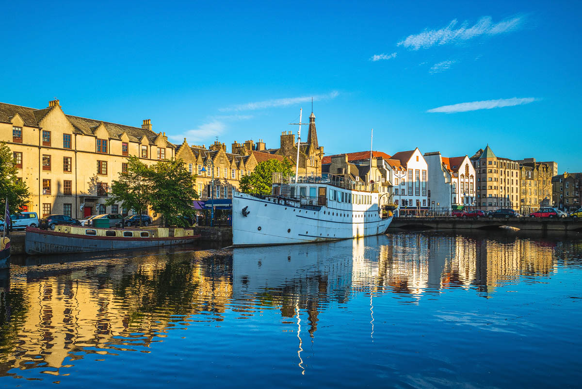 Historic waterfront buildings along The Shore in Leith reflected in the calm waters of the harbour