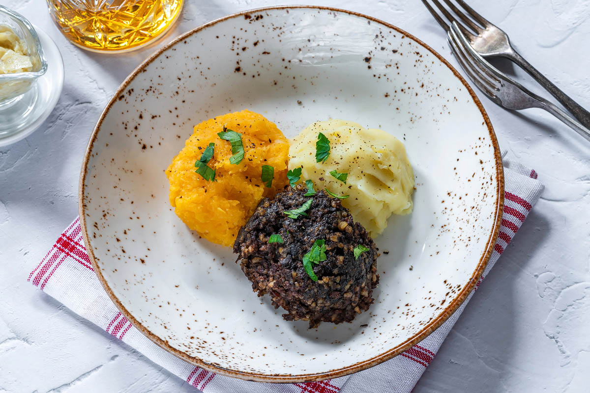 A plate of haggis, neeps and tatties served with a glass of whisky - Scotland's national dish