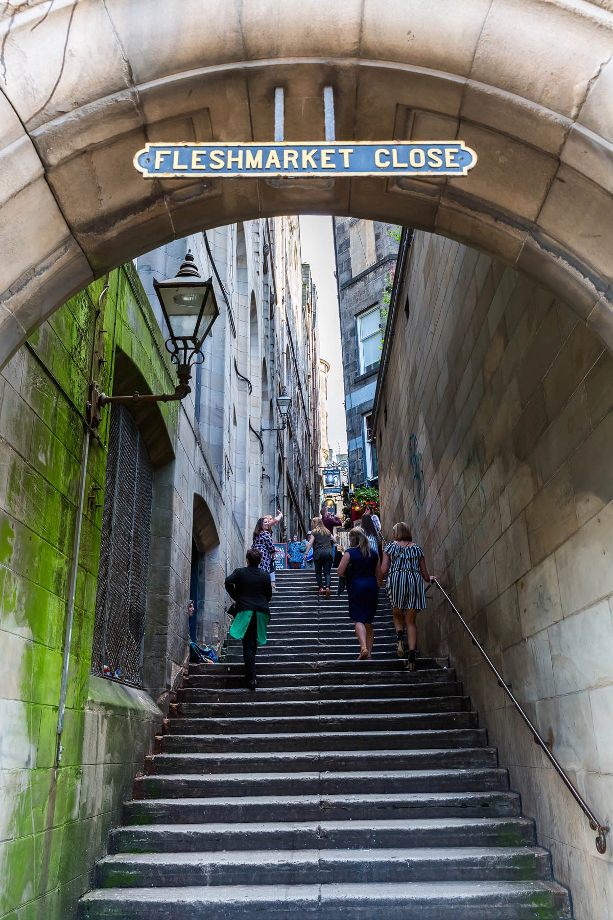 Visitors climbing the steep stone steps of Fleshmarket Close in Edinburgh's Old Town