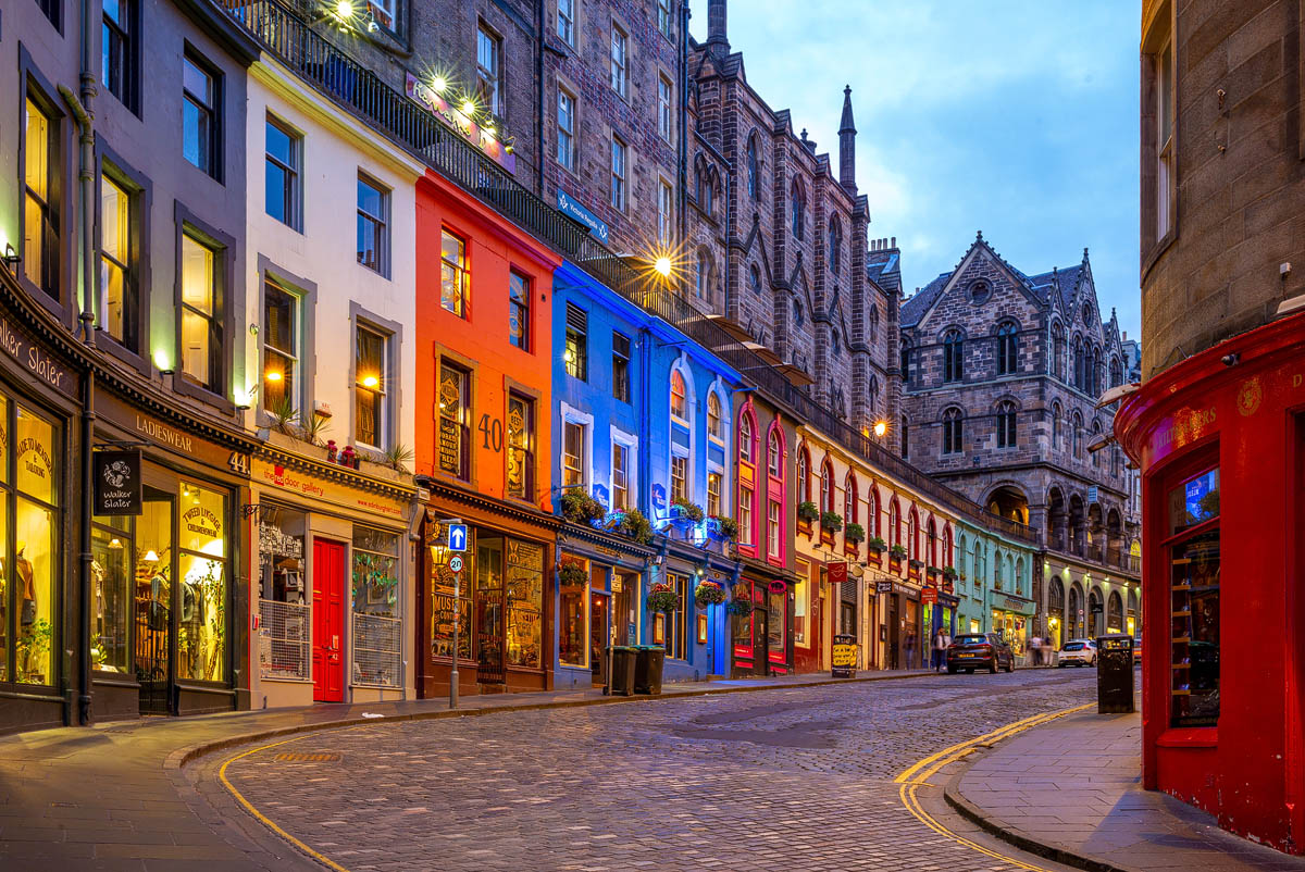 The colourful shopfronts of Victoria Street in Edinburgh's Old Town illuminated at dusk