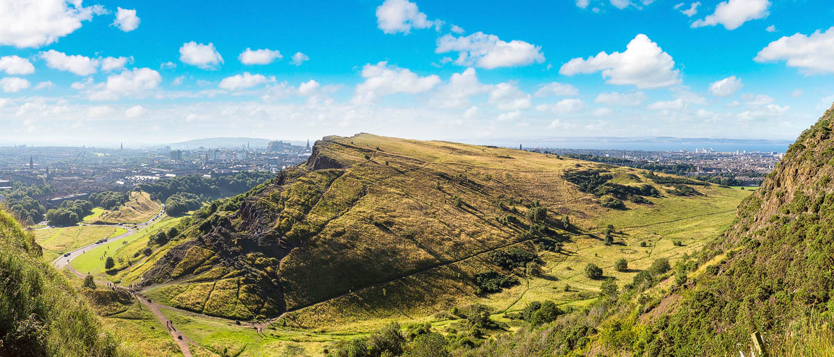Panoramic view of Arthur's Seat and the Salisbury Crags in Holyrood Park with Edinburgh's skyline in the distance