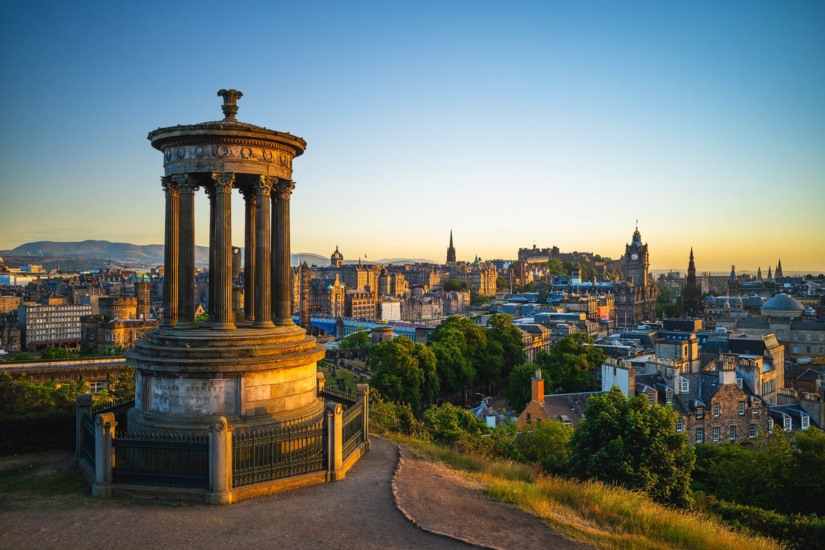 The Dugald Stewart Monument on Calton Hill bathed in golden hour light with Edinburgh's skyline beyond