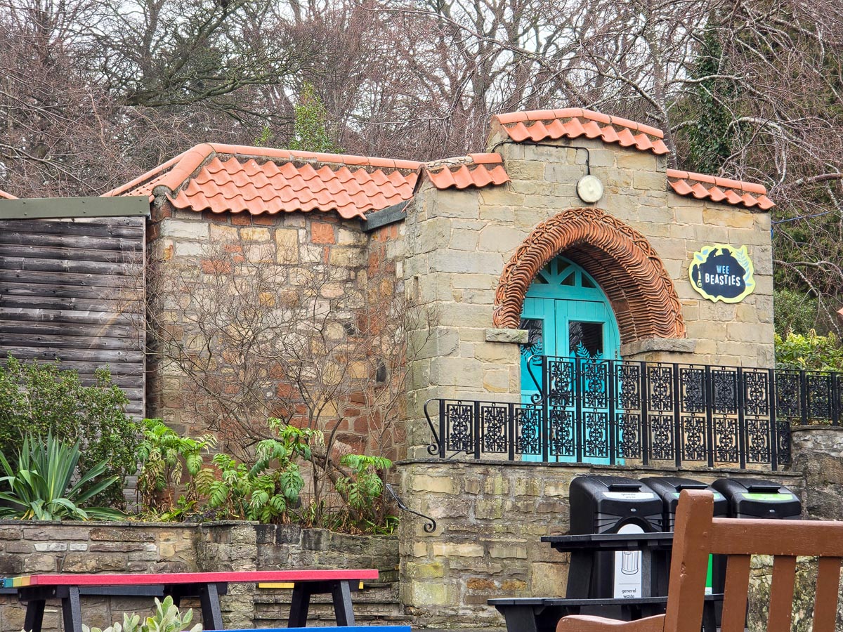 The stone exterior of the Wee Beasties building at Edinburgh Zoo with terracotta roof and arched entrance