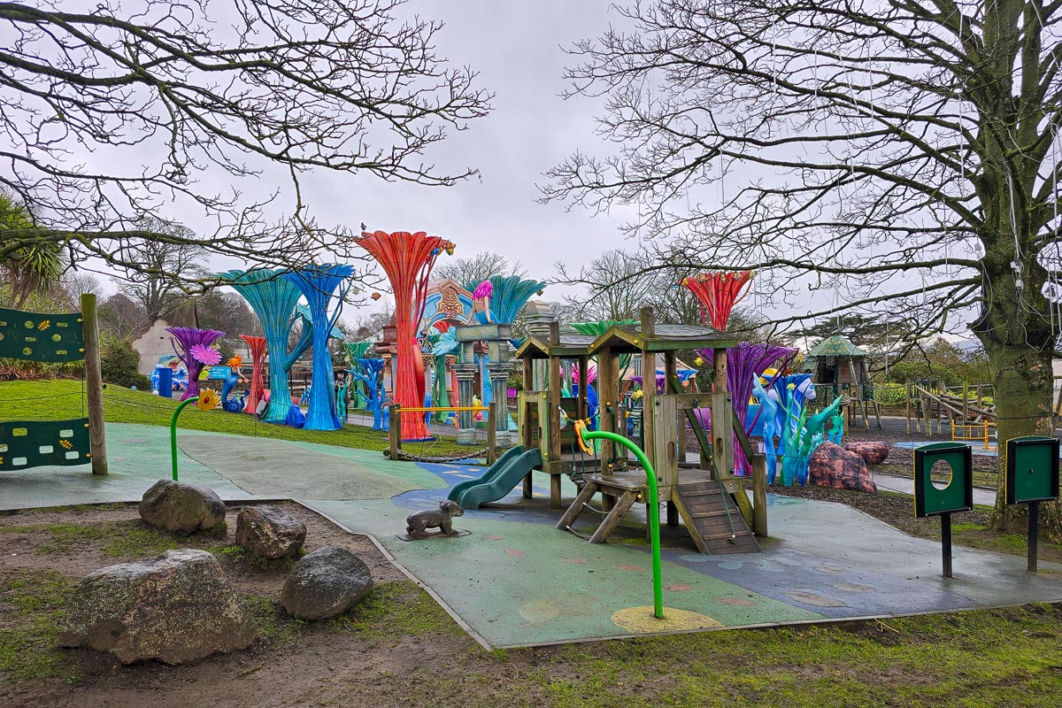 The children's play area at Edinburgh Zoo with wooden climbing frames and colourful lantern sculptures in the background