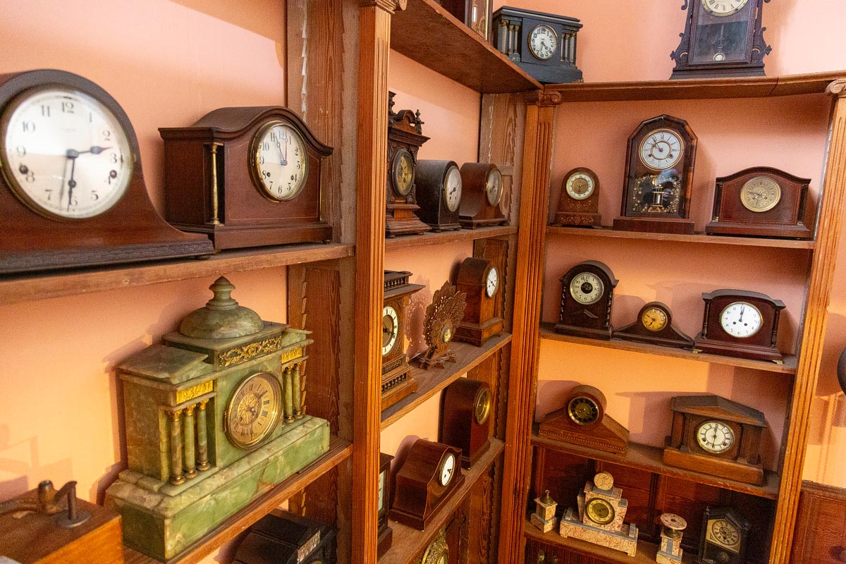 A collection of antique mantel clocks and timepieces displayed on shelves inside the museum