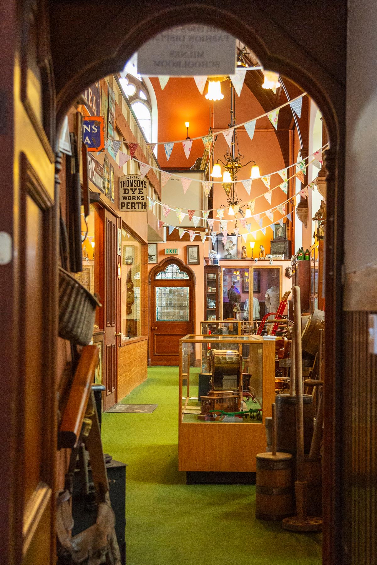 A view through an archway into the main hall of the museum, with bunting and vintage signs creating a warm atmosphere