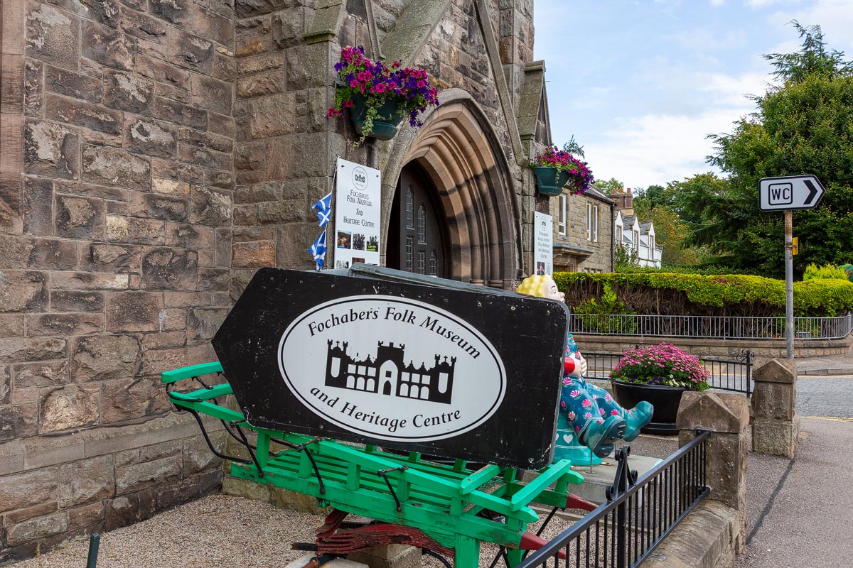 The Fochabers Folk Museum entrance sign displayed on a green cart outside the former church building