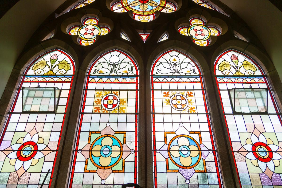 Ornate stained glass windows featuring floral and geometric designs inside the former Pringle Church