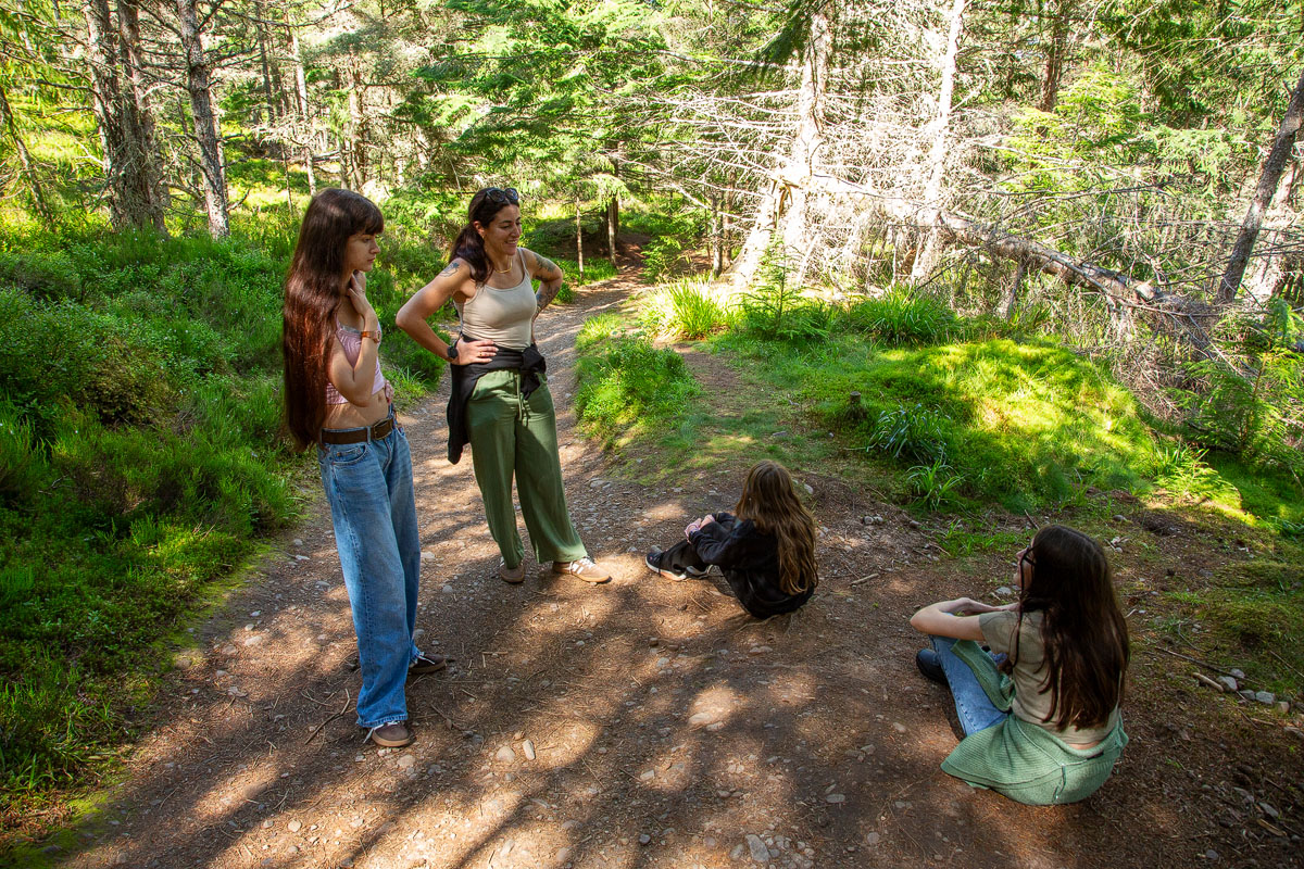 Janette and the three daughters pausing to rest and chat at a junction clearing on the wooded trail
