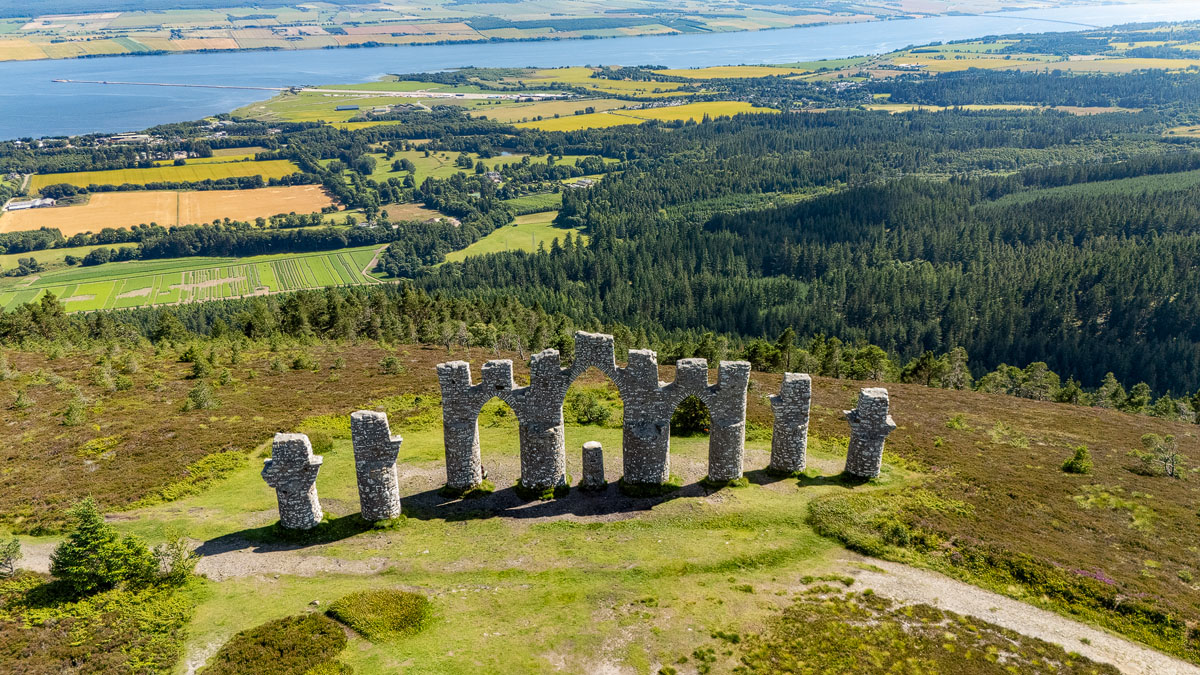 Aerial drone view of the Fyrish Monument from above with the Cromarty Firth, fields and Invergordon beyond