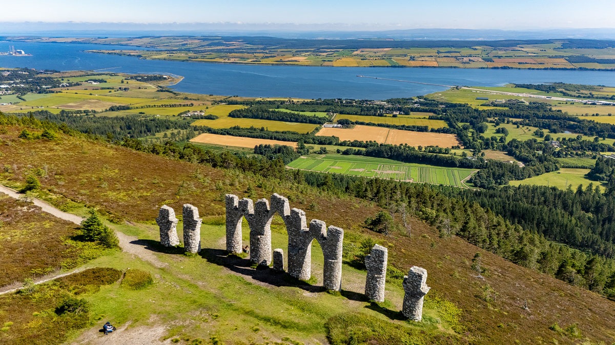 Drone view from the seaward side of the monument with the full sweep of the Cromarty Firth and a person for scale