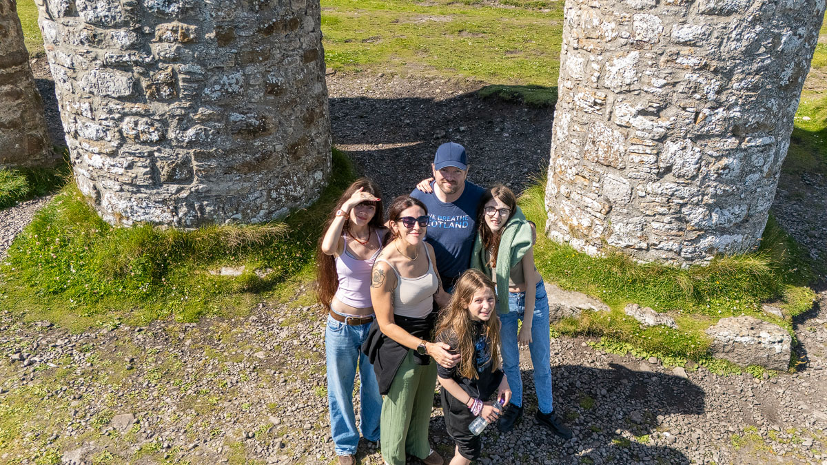 Group photo of the whole family of five looking up at the drone from between the towers of the monument