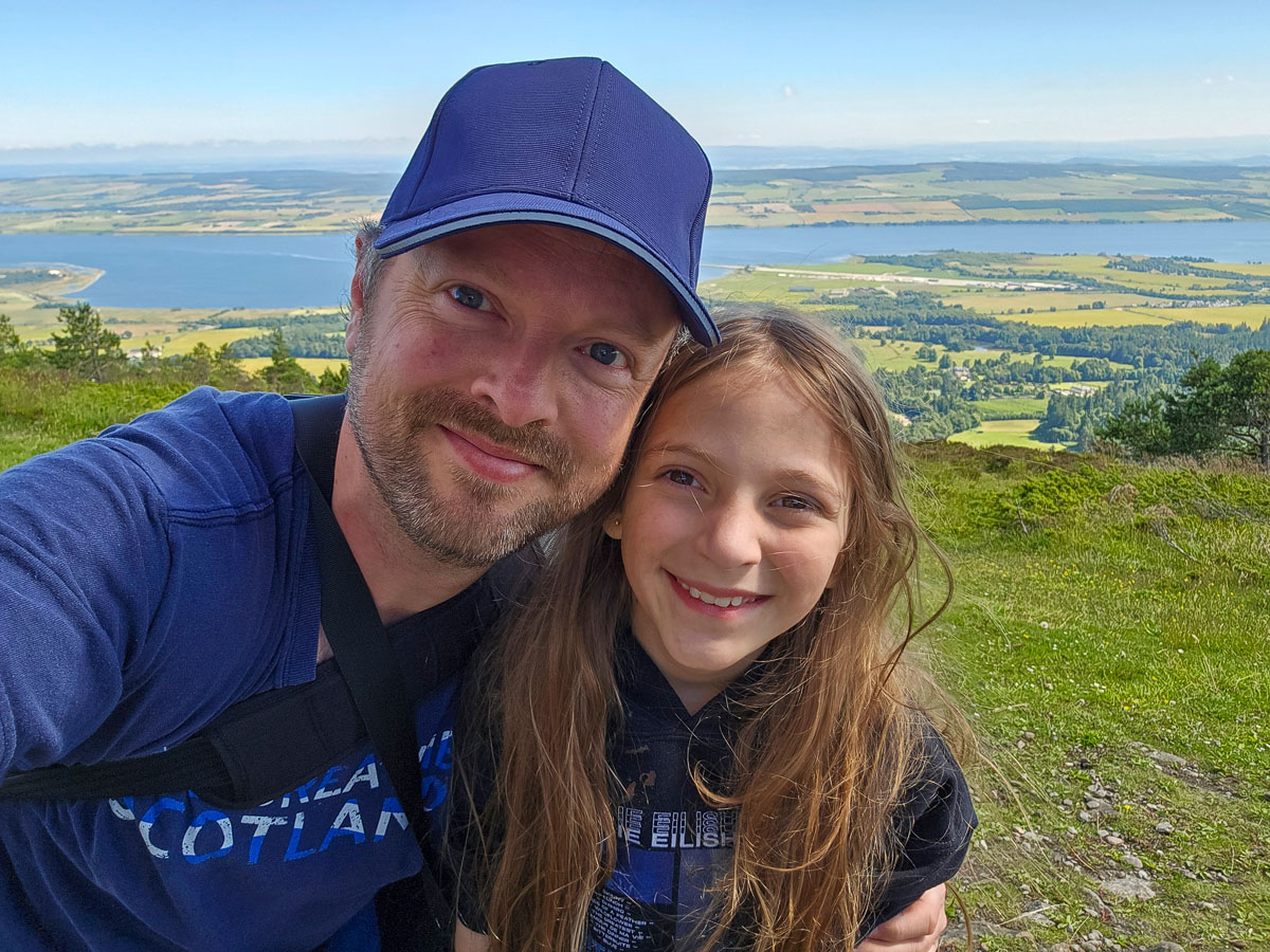 Selfie of Chris and his youngest daughter Lauren at the summit with the Cromarty Firth panorama behind