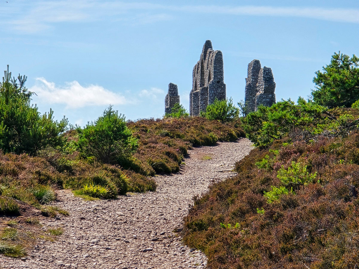 Looking up the stony path at the ruined flanking pillars of the Fyrish Monument silhouetted against the sky