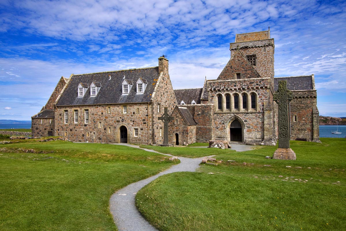 Iona Abbey with a Celtic high cross in the foreground and a winding path leading to the entrance