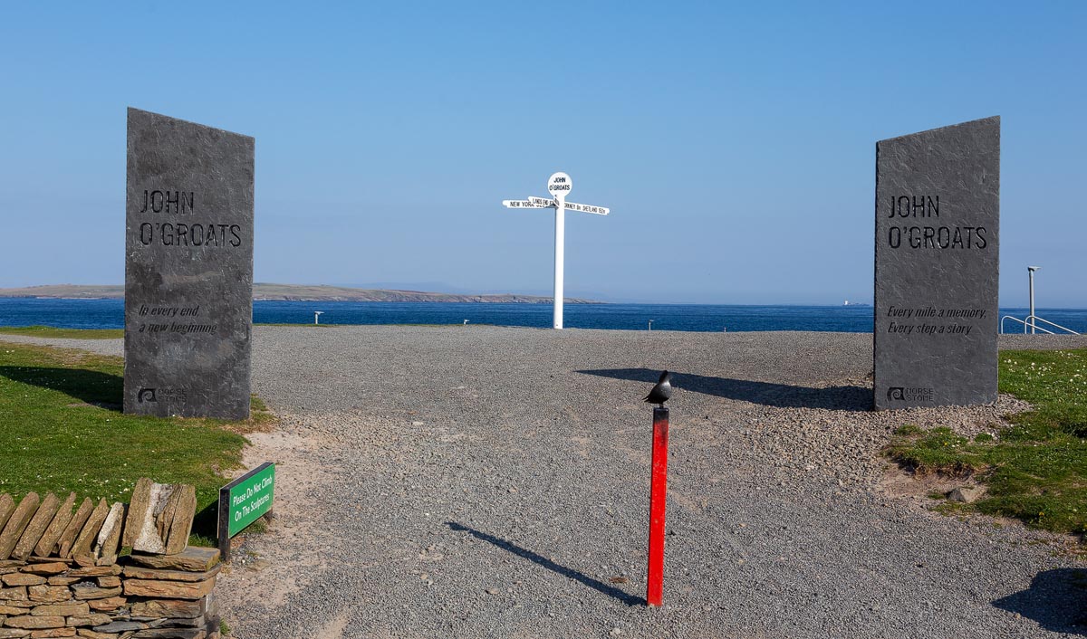 The iconic John o' Groats signpost framed between two Caithness slate standing stones