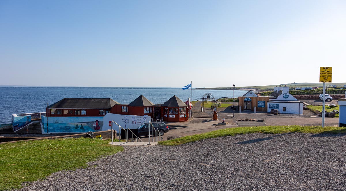 An overview of the John o' Groats harbour area showing the gift shops, visitor information centre and Scottish saltire