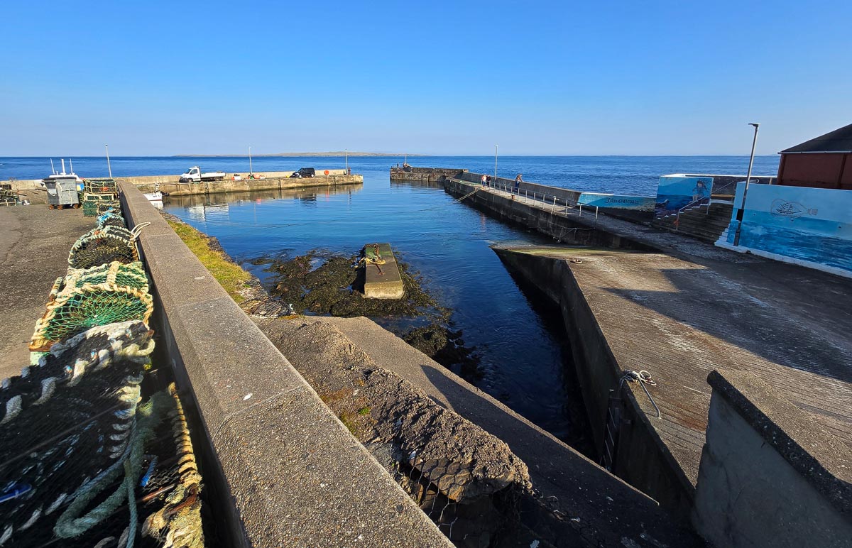 John o' Groats harbour with lobster creels stacked along the quayside and views across to Orkney
