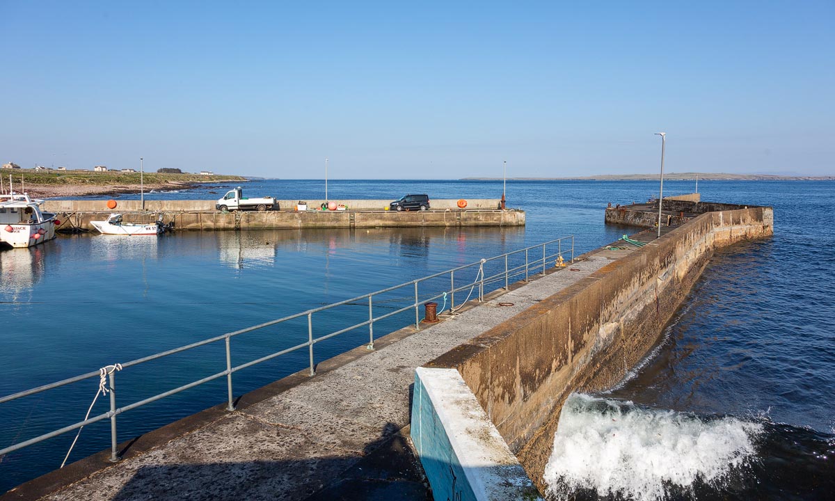 John o' Groats harbour with its stone pier and calm blue waters looking out towards the Pentland Firth
