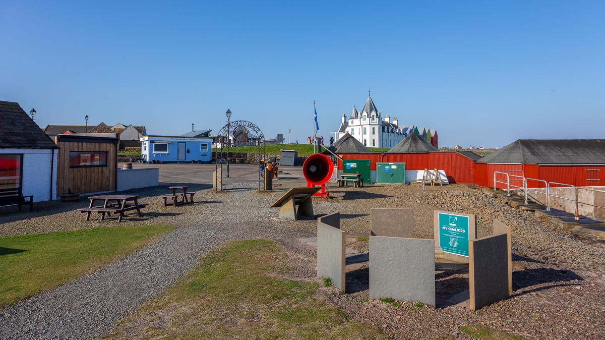 The harbour area at John o' Groats showing the memorial, red foghorn, and the Inn in the background